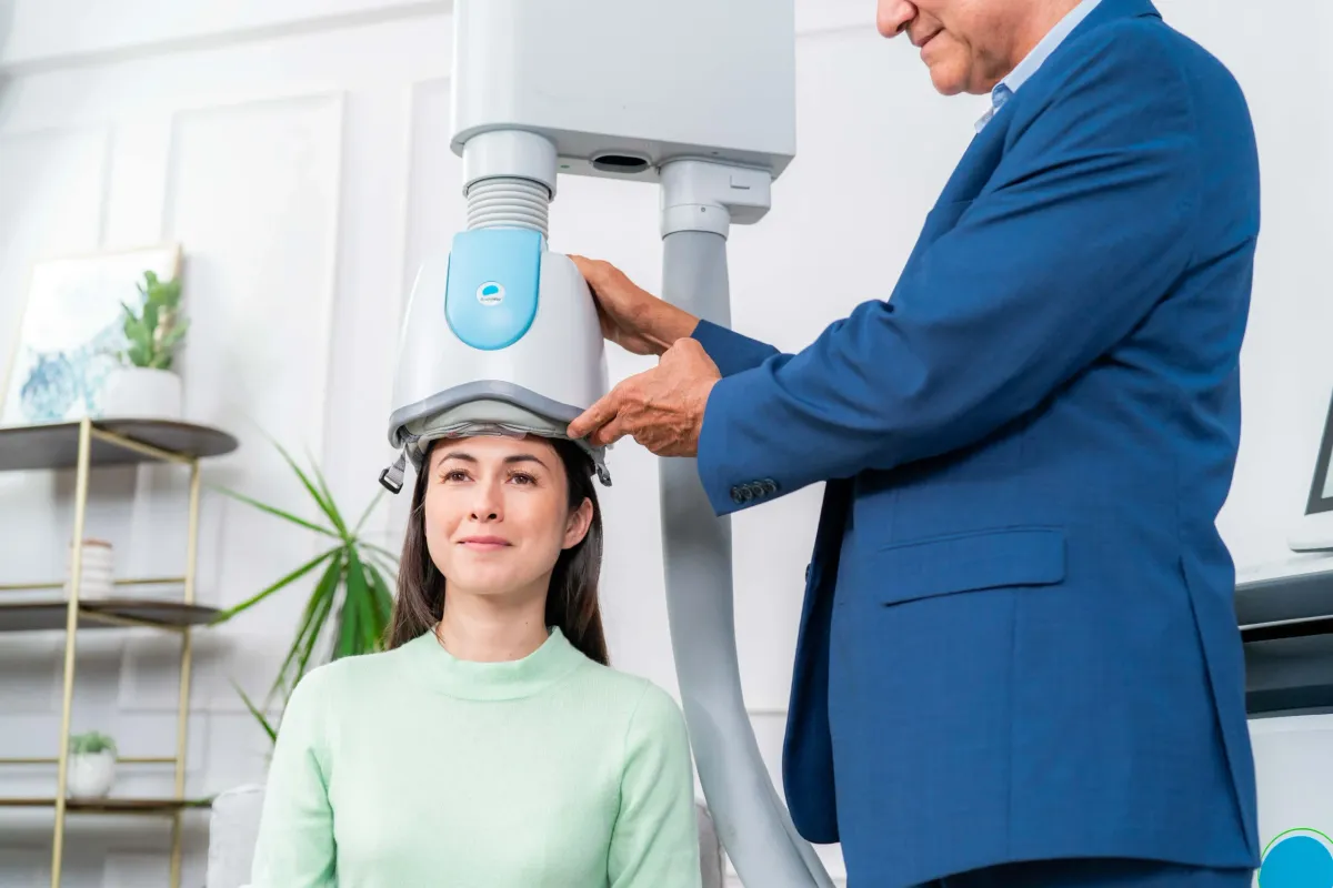 Provider positioning a BrainsWay Deep TMS helmet on a seated person
