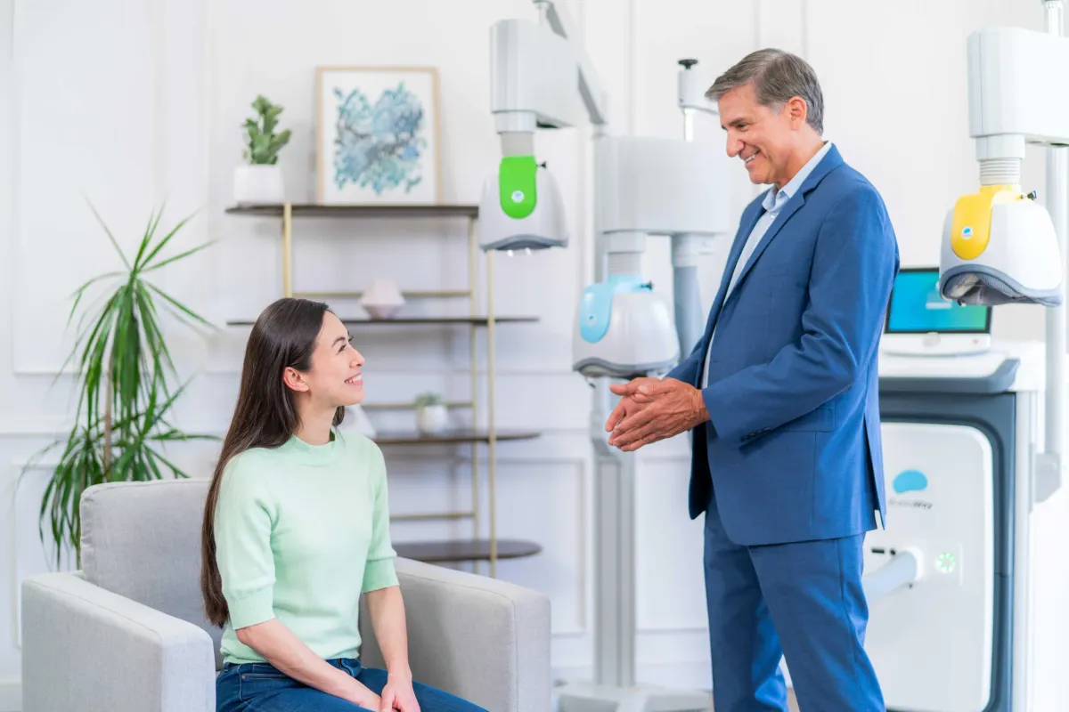 Provider speaking with a seated person near BrainsWay Deep TMS equipment