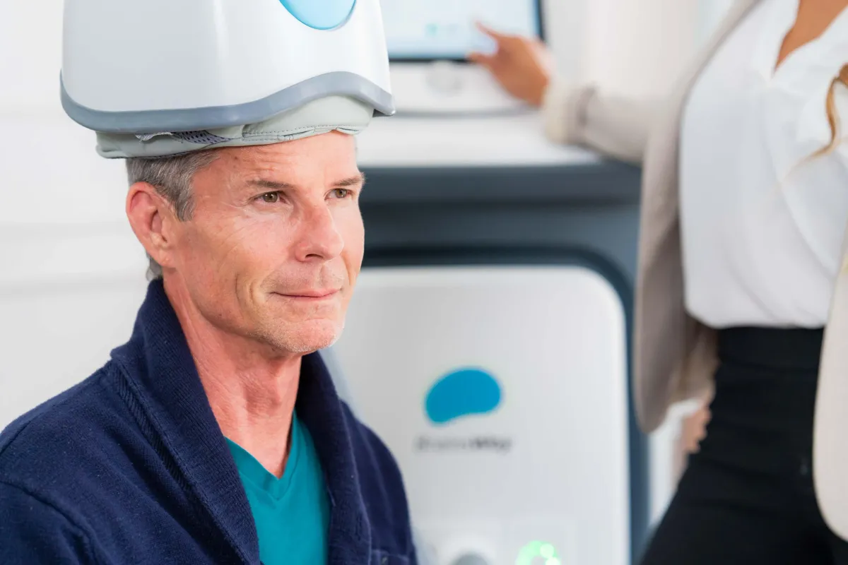 Person wearing a BrainsWay Deep TMS helmet during an in-office visit