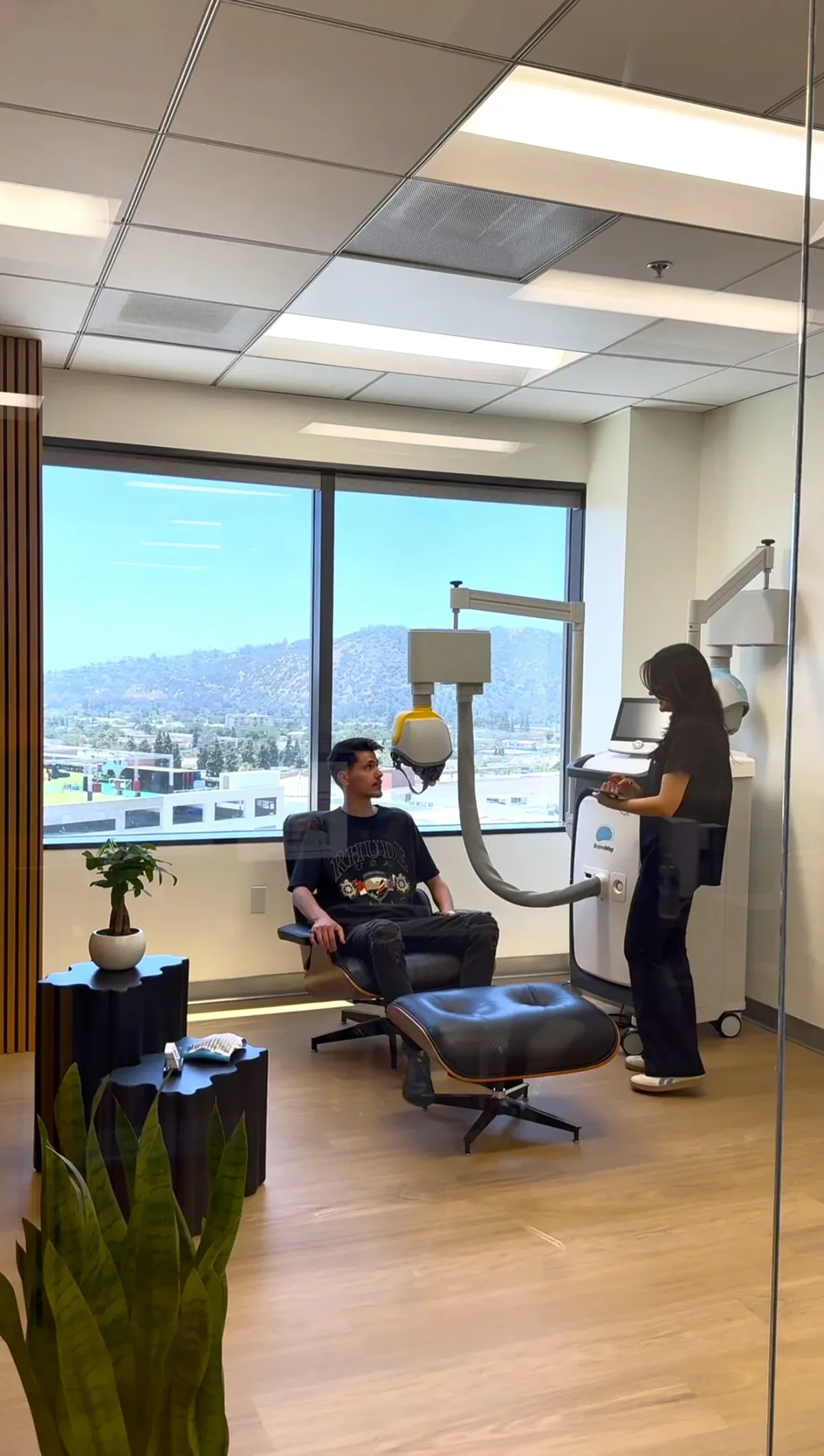 A Breakthrough TMS clinician operating the BrainsWay Deep TMS system for a person seated in the treatment room